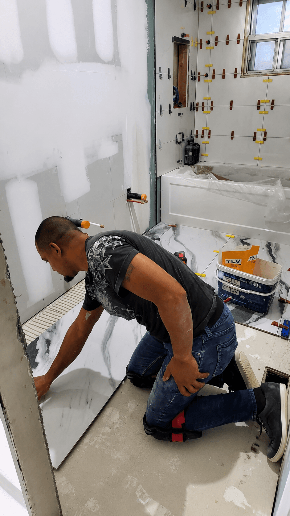 Crew member installing tile in a bathroom renovation
